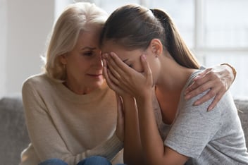 Older woman comforts grieving younger woman through loss