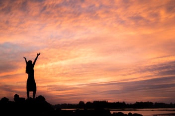 Outline of a woman taking in a beautiful sunrise
