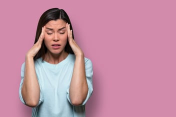 Young woman holding her head in her hands because she’s overwhelmed and stressed