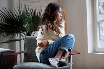 anxious girl sits alone worrying and biting nails