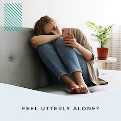girl sits on couch looking at phone and feeling alone